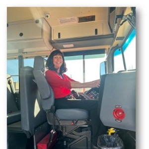 a woman smiles for a photo inside a bus